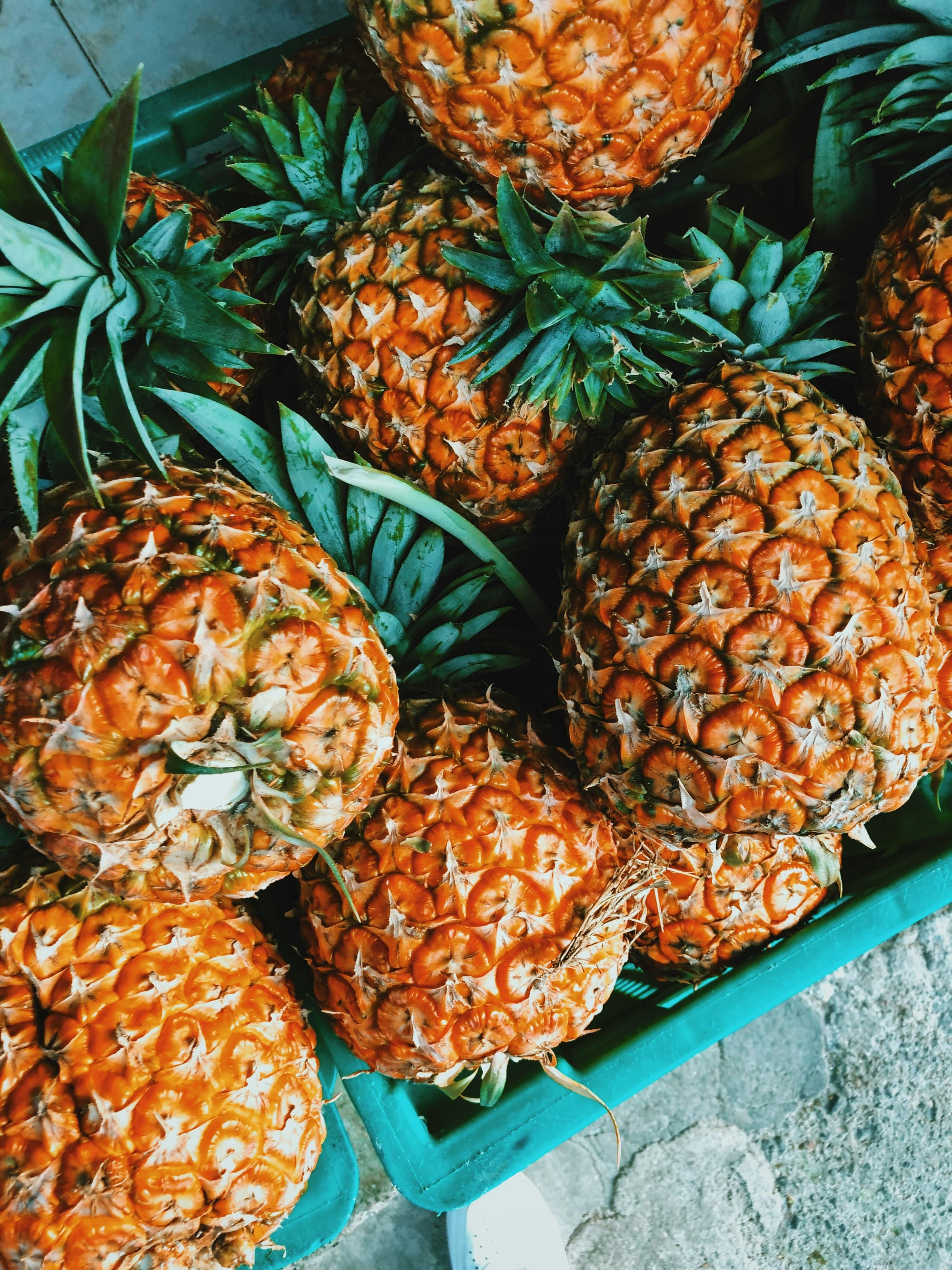 Overhead shot of pineapples in a turquoise box on a road in Mexico ready to be made into tepache