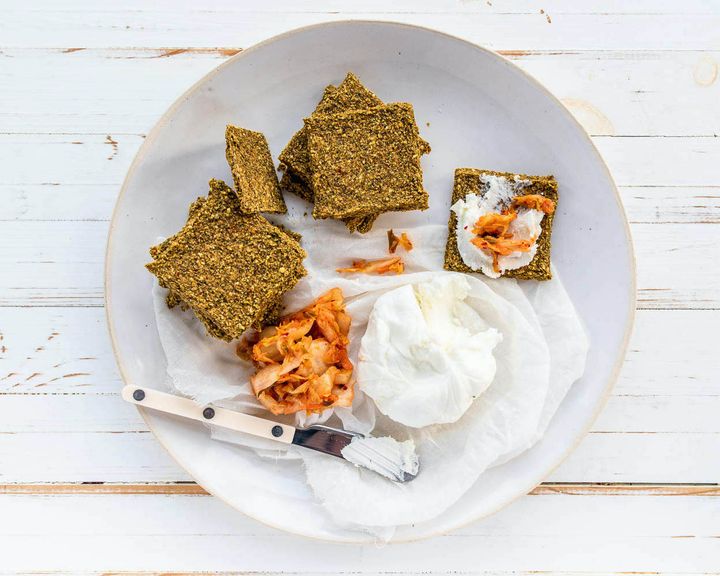 kimchi kale crackers topped with nut cheese and kimchi on a white background