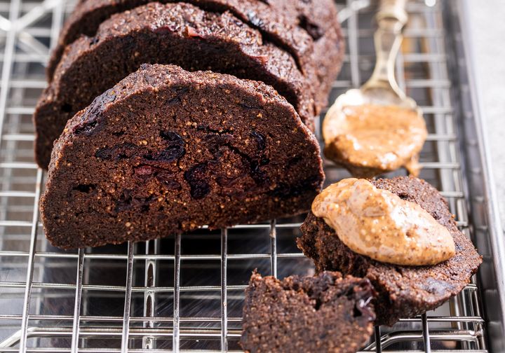 Raw vegan chocolate cherry bread on a silver baking tray and wire rack with almond butter