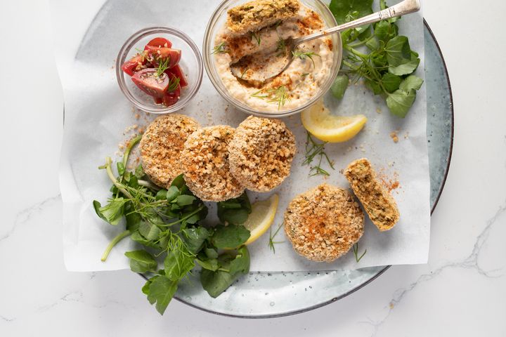 Fermented raw vegan crab cakes on a light blue plate and white marble background