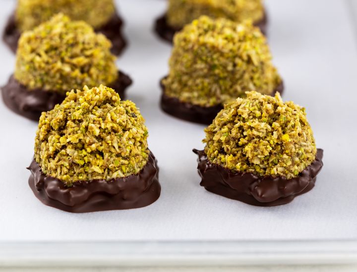 Raw vegan Chinese five spice macaroons dipped in chocolate on white backing parchment and a silver tray