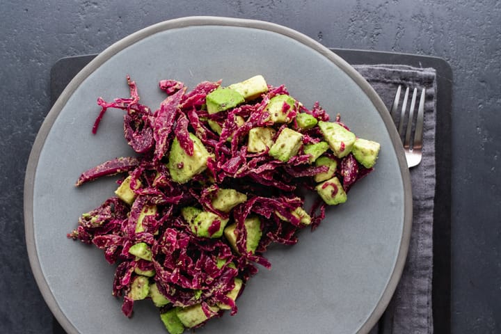 Sauerkraut, avocado and cumin on a grey plate and dark grey background