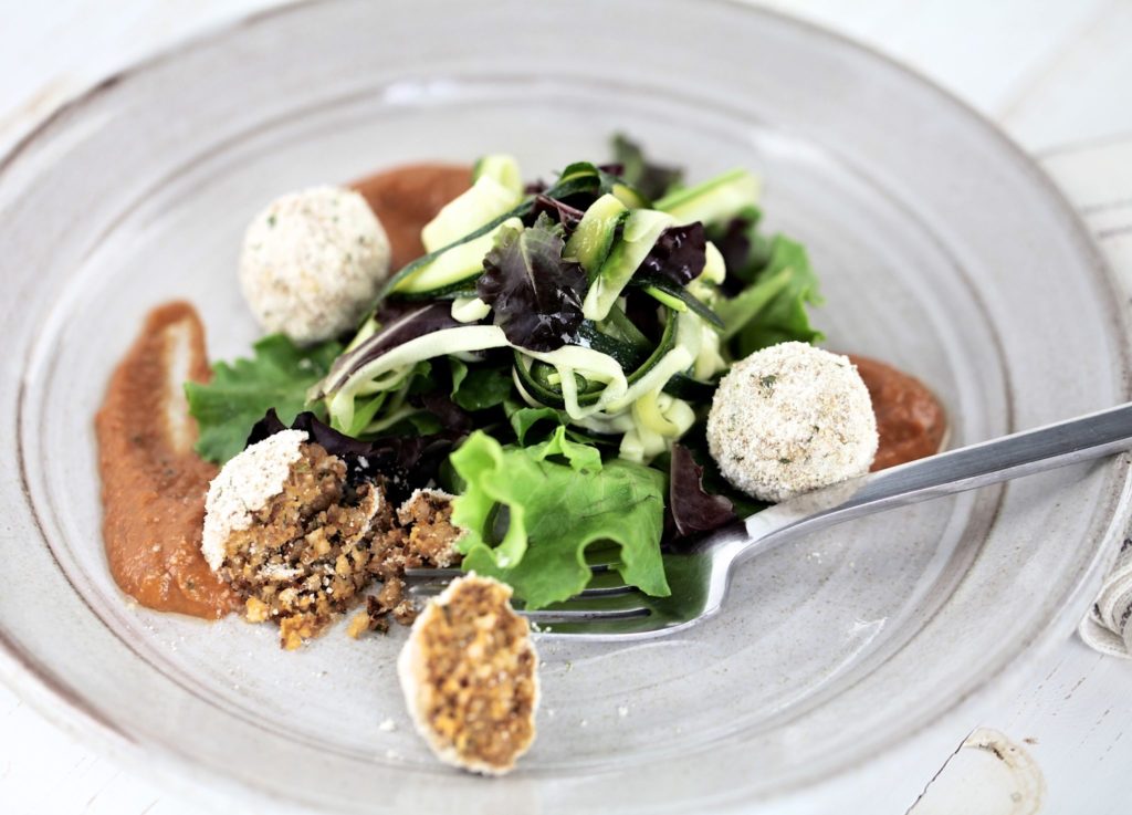 Salsa finta with almond polpetta on a grey plate with a fork and salad