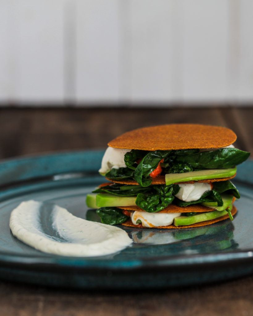 Sour cream avocado napoleon on a blue plate and wooden background