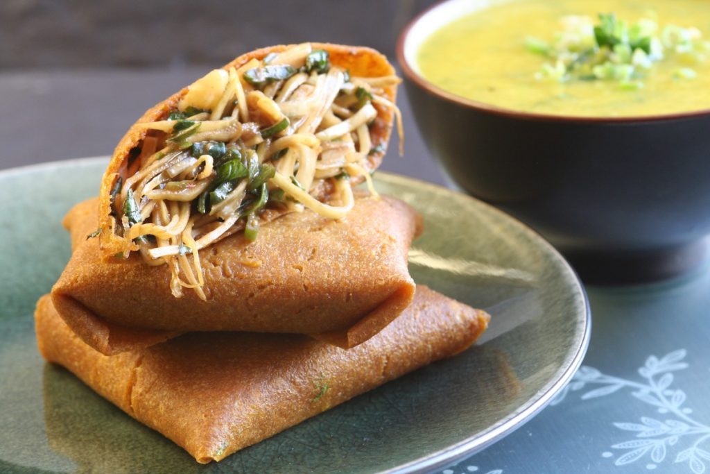 Curried cabbage pillows on a green plate with sauce in the background