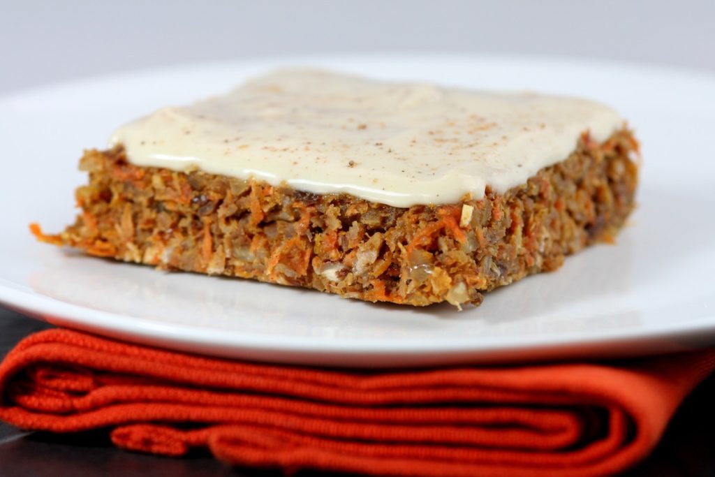Raw carrot cake on a white plate with an orange napkin