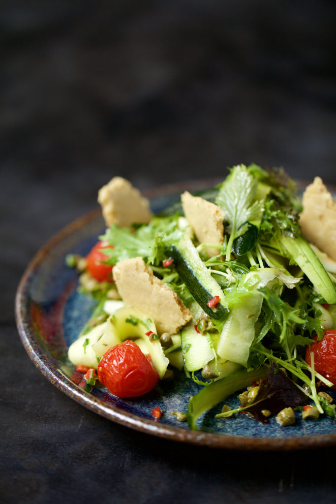 The Chilli Courgette Pasta is serve in a ceramic bowl on a dark colored table.