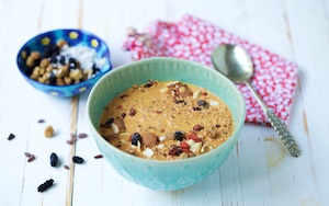 Five minute muesli in a blue bowl with goji berry almond milk, on a white background