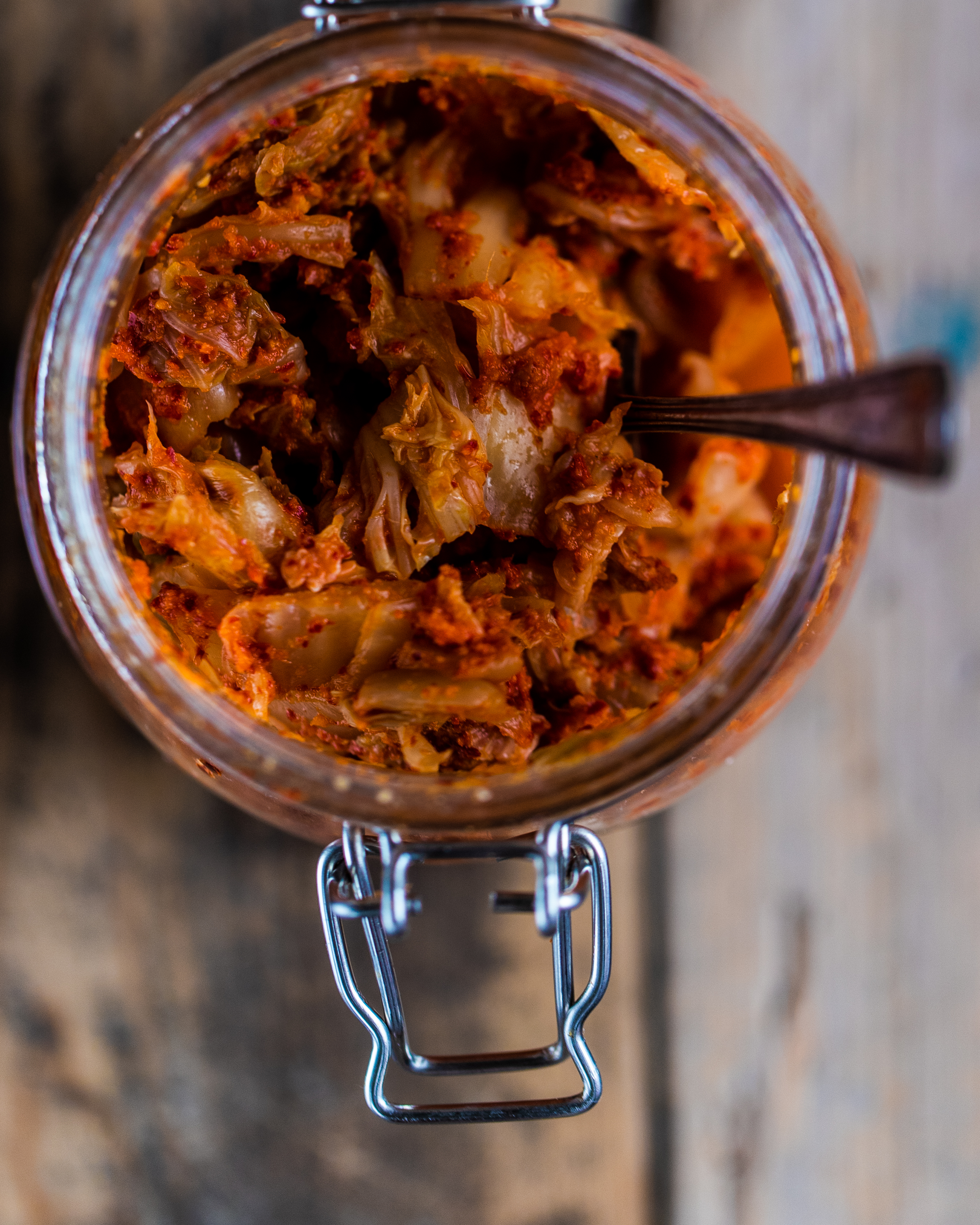 Overhead shot of vegan kimchi in a glass jar on a wooden surface