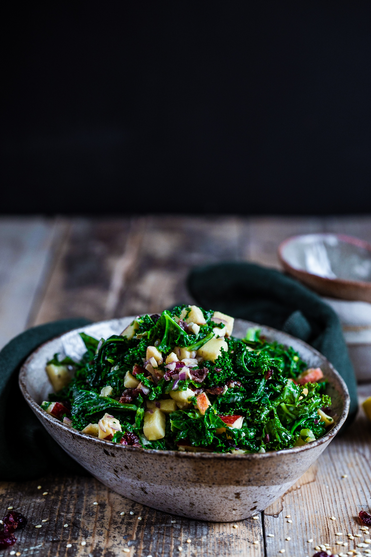 Cranberry & apple kale salad in a bowl on a wooden background. 