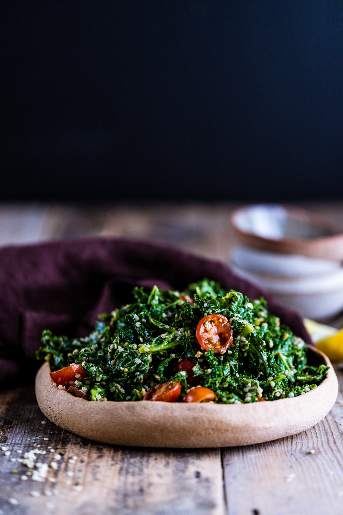 Kale avocado salad in a brown bowl on a wooden surface
