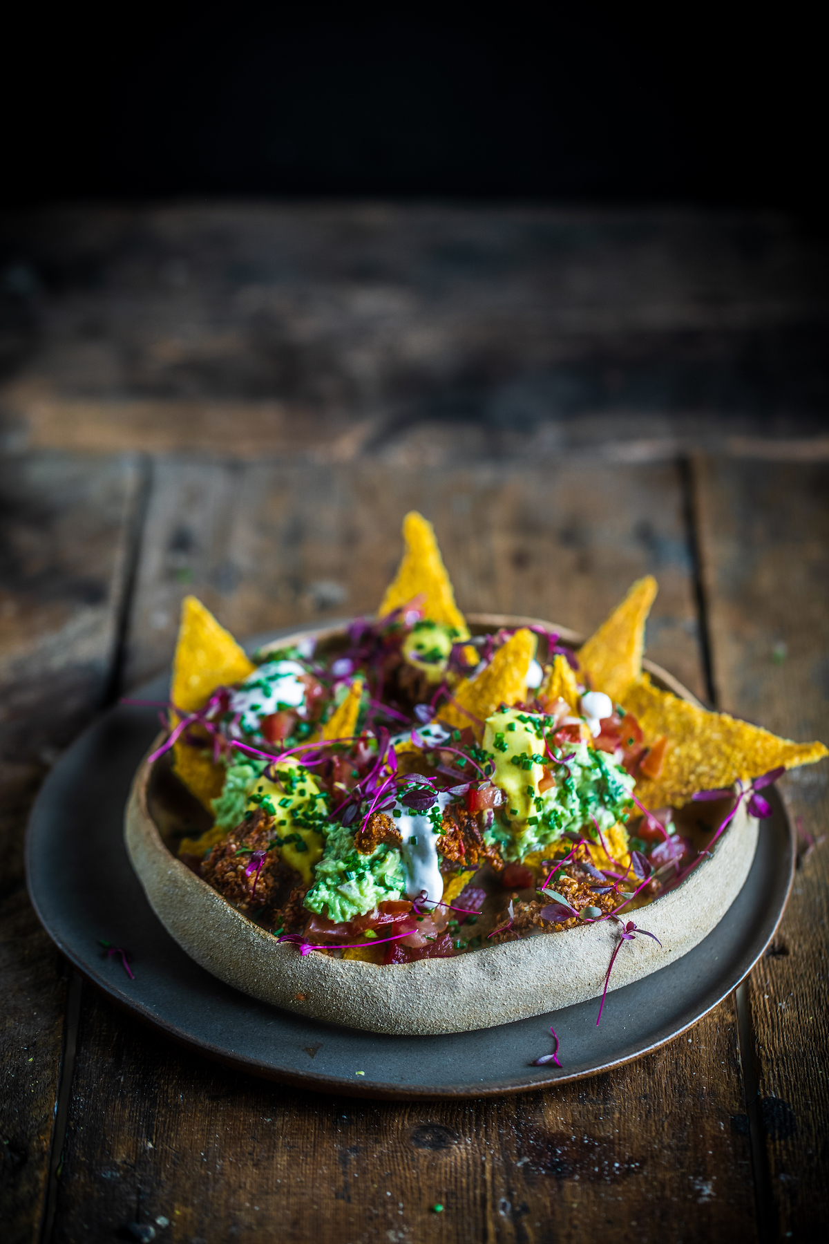 Raw vegan nachos in a brown bowl on a wooden background