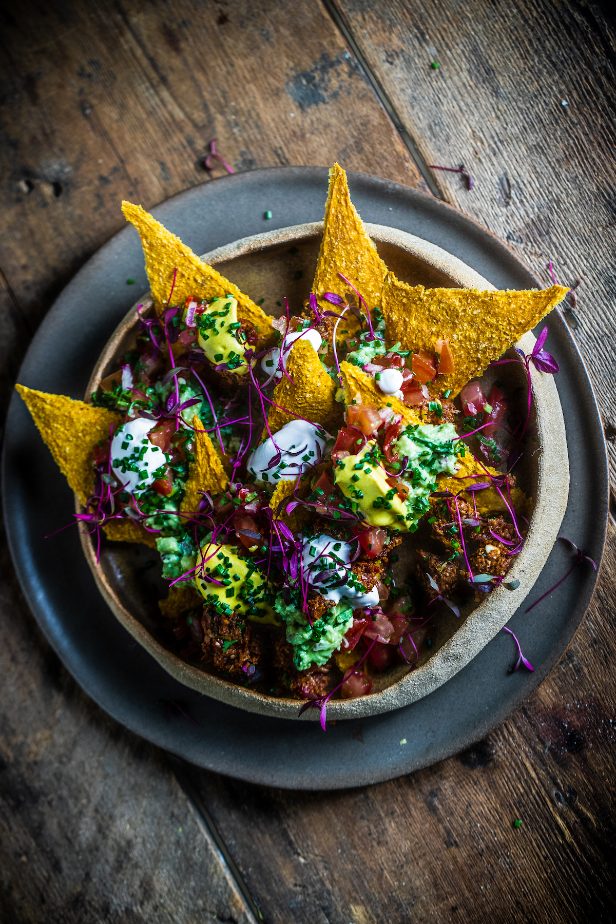 Raw vegan nachos in a brown bowl on a wooden background