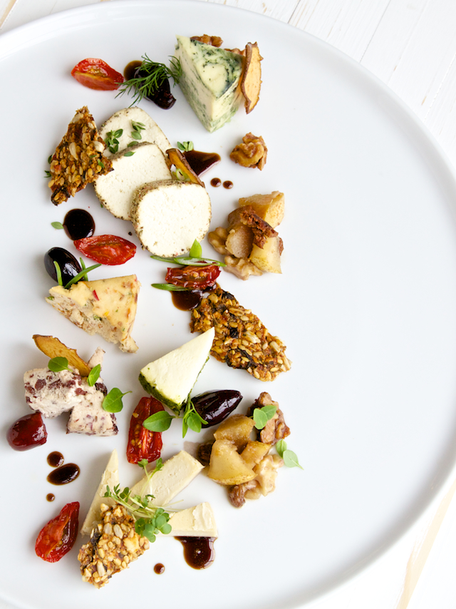 Overhead shot of raw Vegan tree nut cheeses on a plate with accompaniments