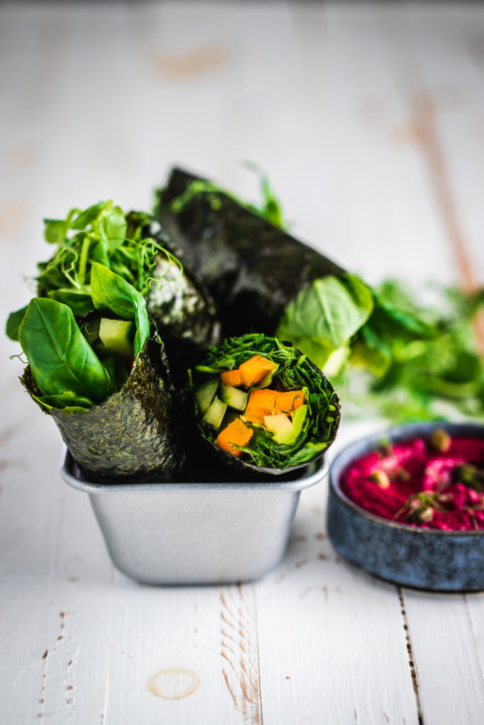 Raw nori wraps with a beet dip in a tray on a white board