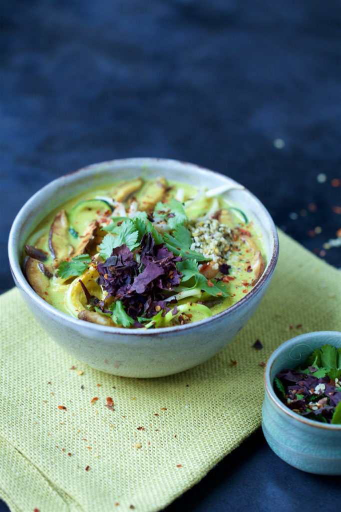 This Malaysian Squash Noodle dish is in a white bowl on top of an Asian textured food place mat.