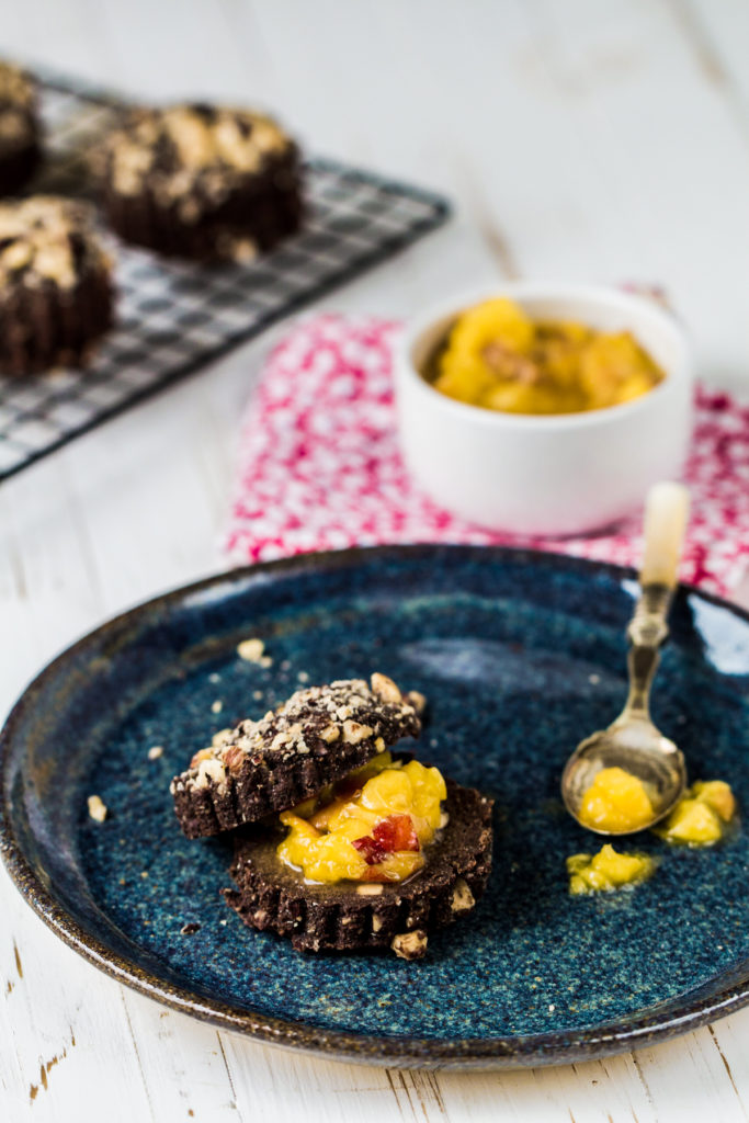 Raw chocolate breakfast roll cut in half with nectarine compote on a blue plate