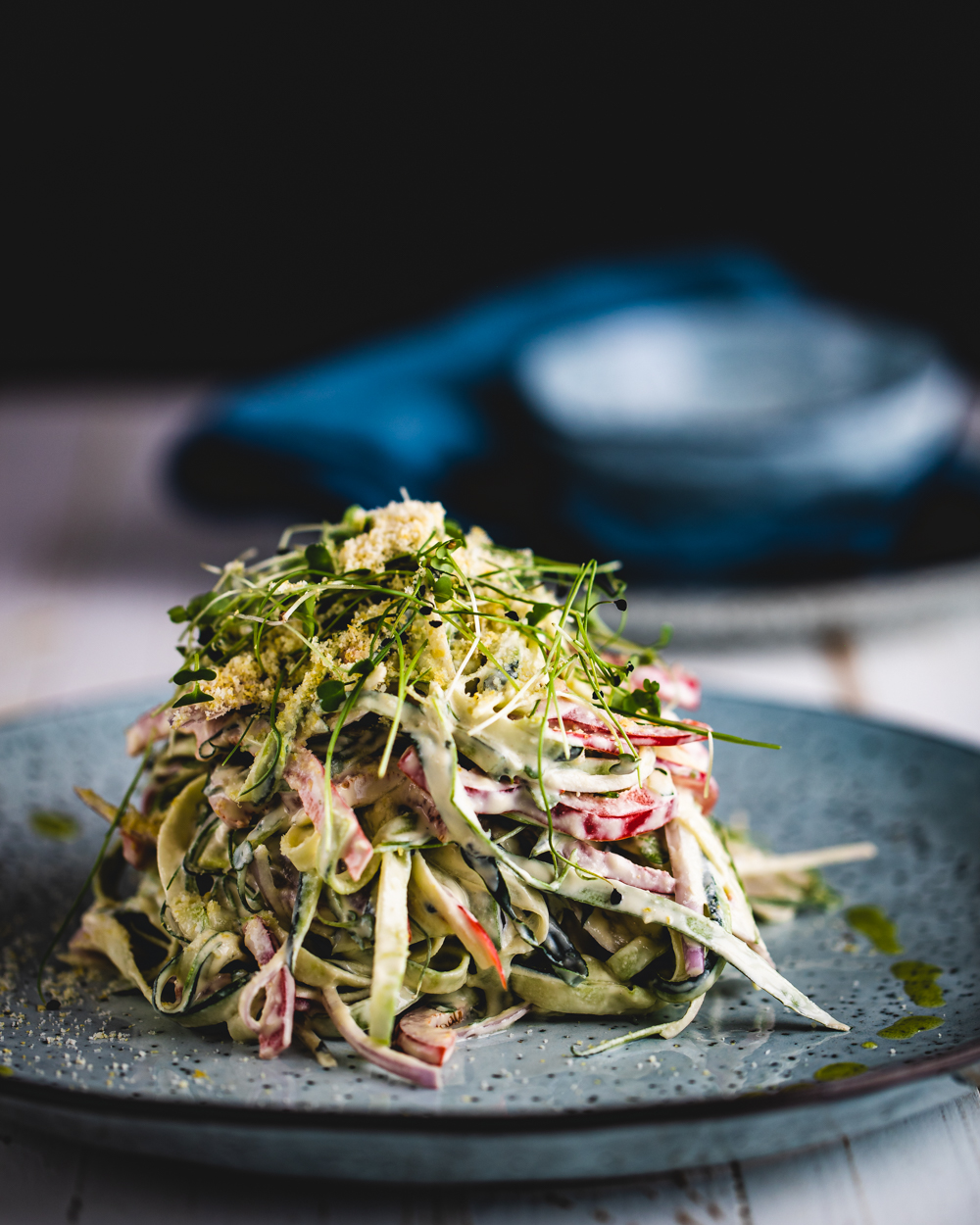 zucchini fettuccine on a blue plate and white wooden surface