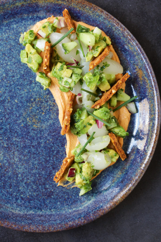 The dish sits on the side of a blue pate on a dark table.