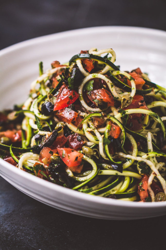 Raw zucchini pasta putanesca in a white bowl