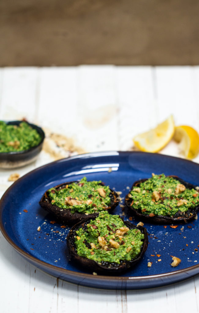 Raw portabellas with rocket pesto on a blue plate on a blue background