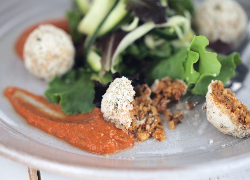 Salsa finta with almond polpetta on a grey plate with a fork and salad