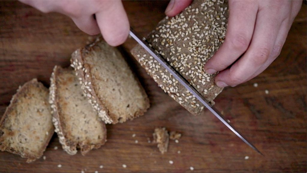 Fermented raw vegan bread overhead shot with three slices already cut on a wooden board