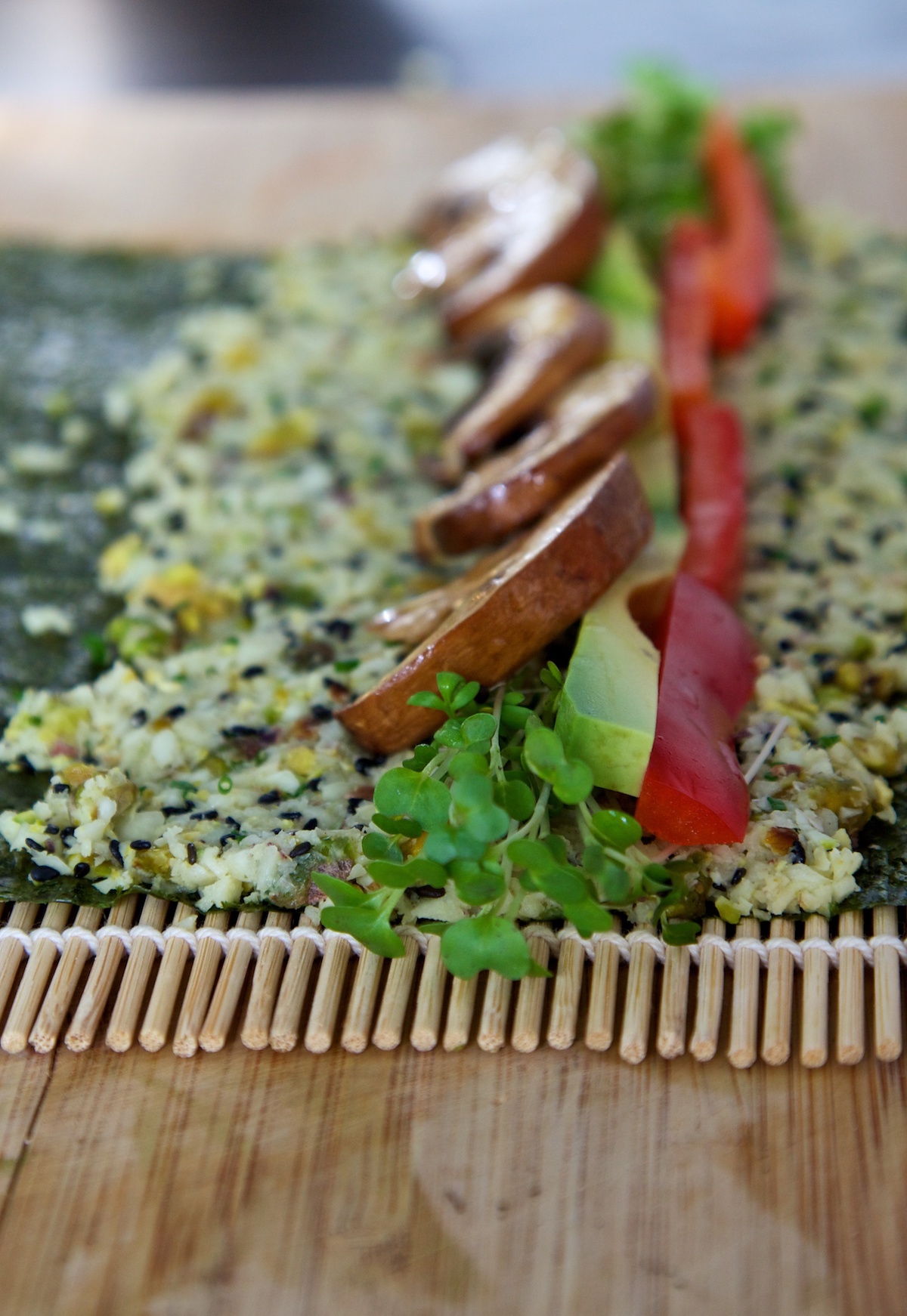 Raw vegan sushi with parsnip rice on a nori sheet, ready to roll on a bamboo mat