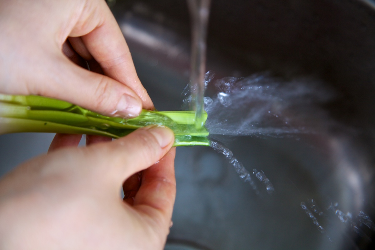 Leeks being washed in a stream of water in a sink