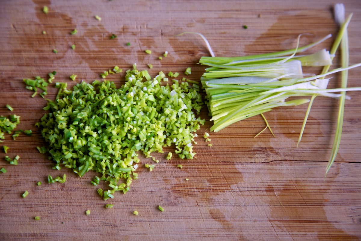 Leeks that have been finely chopped on a bamboo chopping board