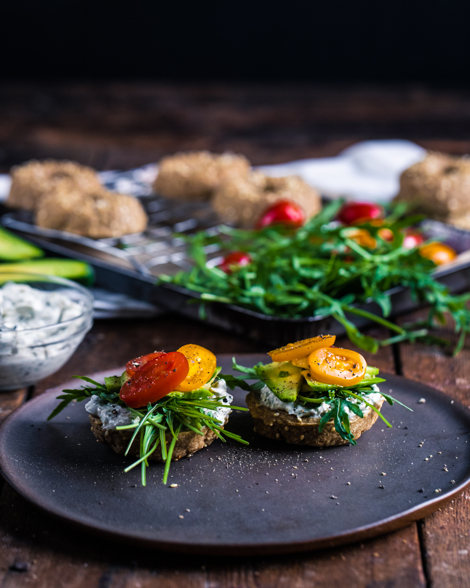 raw food vegan bagels on a grey plate with ingredients in the background