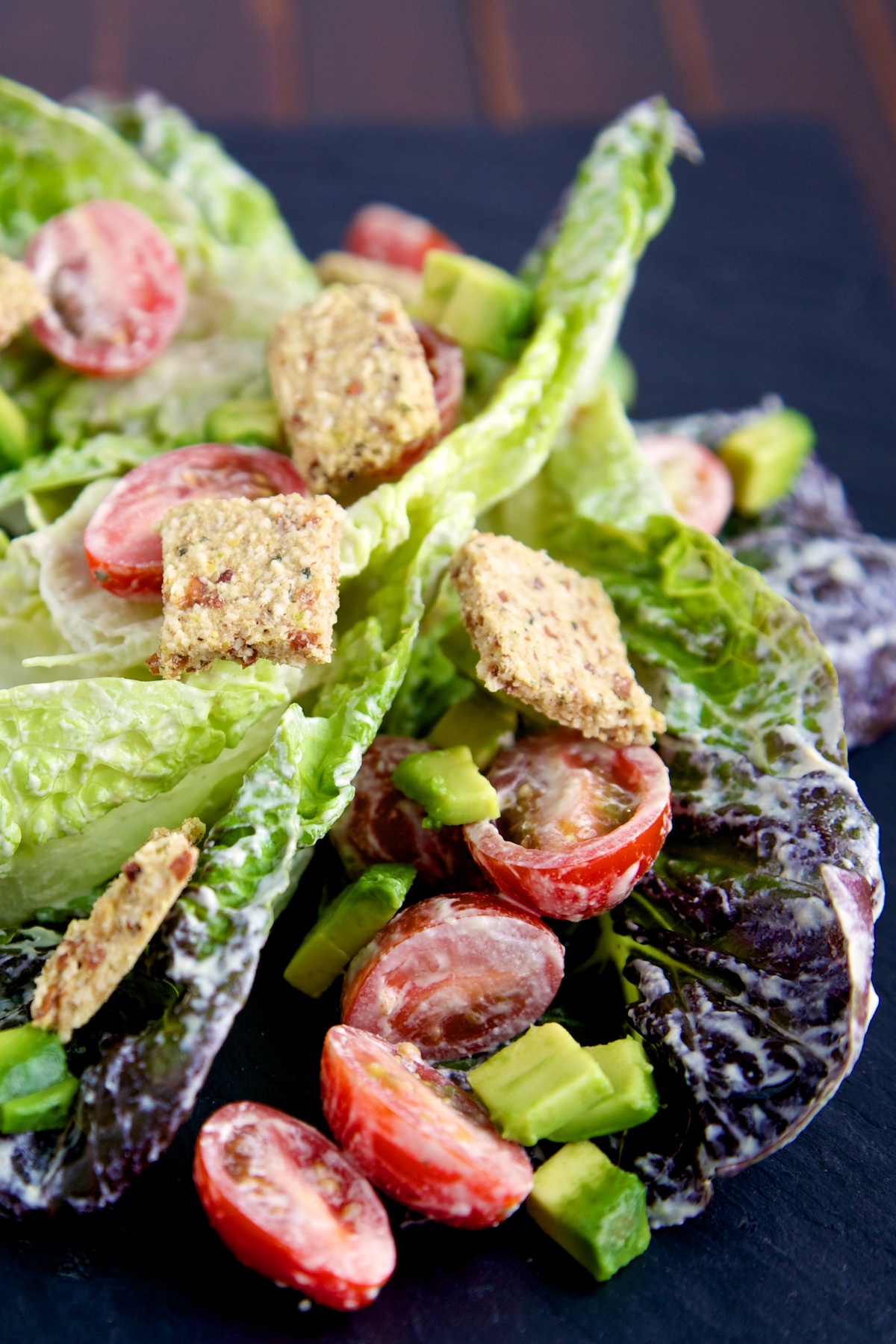 raw vegan caesar salad with croutons on a black background
