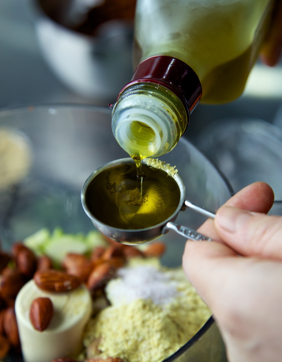 someone pouring olive oil into a measuring spoon