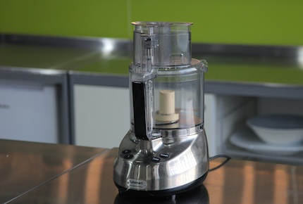 Cuisinart food processor on a steel bench with a green background