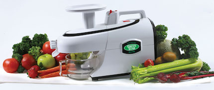 Greenstar Elite juicer on a white background surrounded by fruit and veg