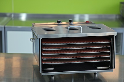 Stainless steel TSM dehydrator with the door off on a steel bench