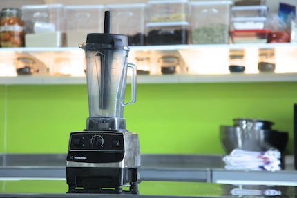 Vitamix on a steel bench with a green background