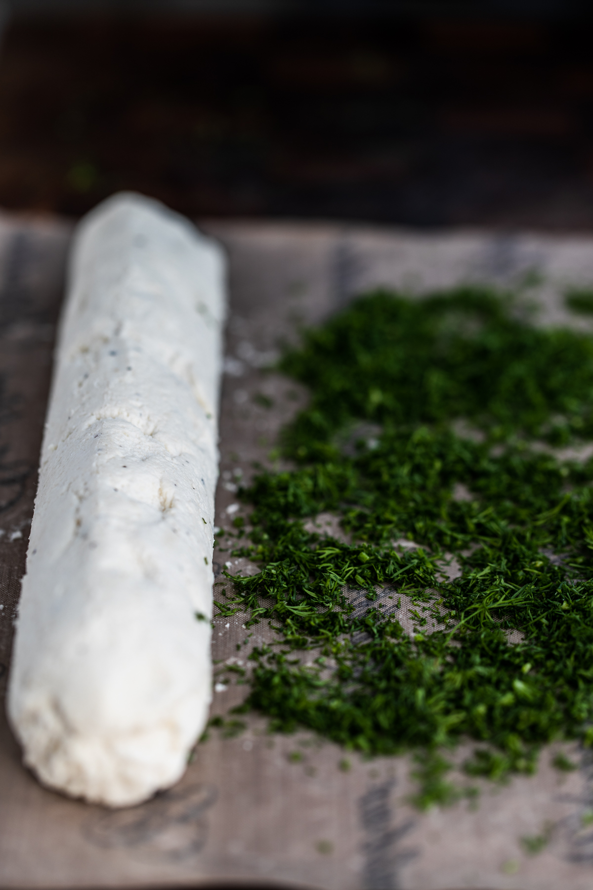 Chopped dill next to a macadamia log on a nonstick dehydrator sheet