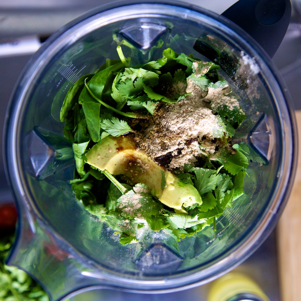 Top down view of raw avocado, spinach and lime soup ingredients in the Vitamix jug, before being blended.