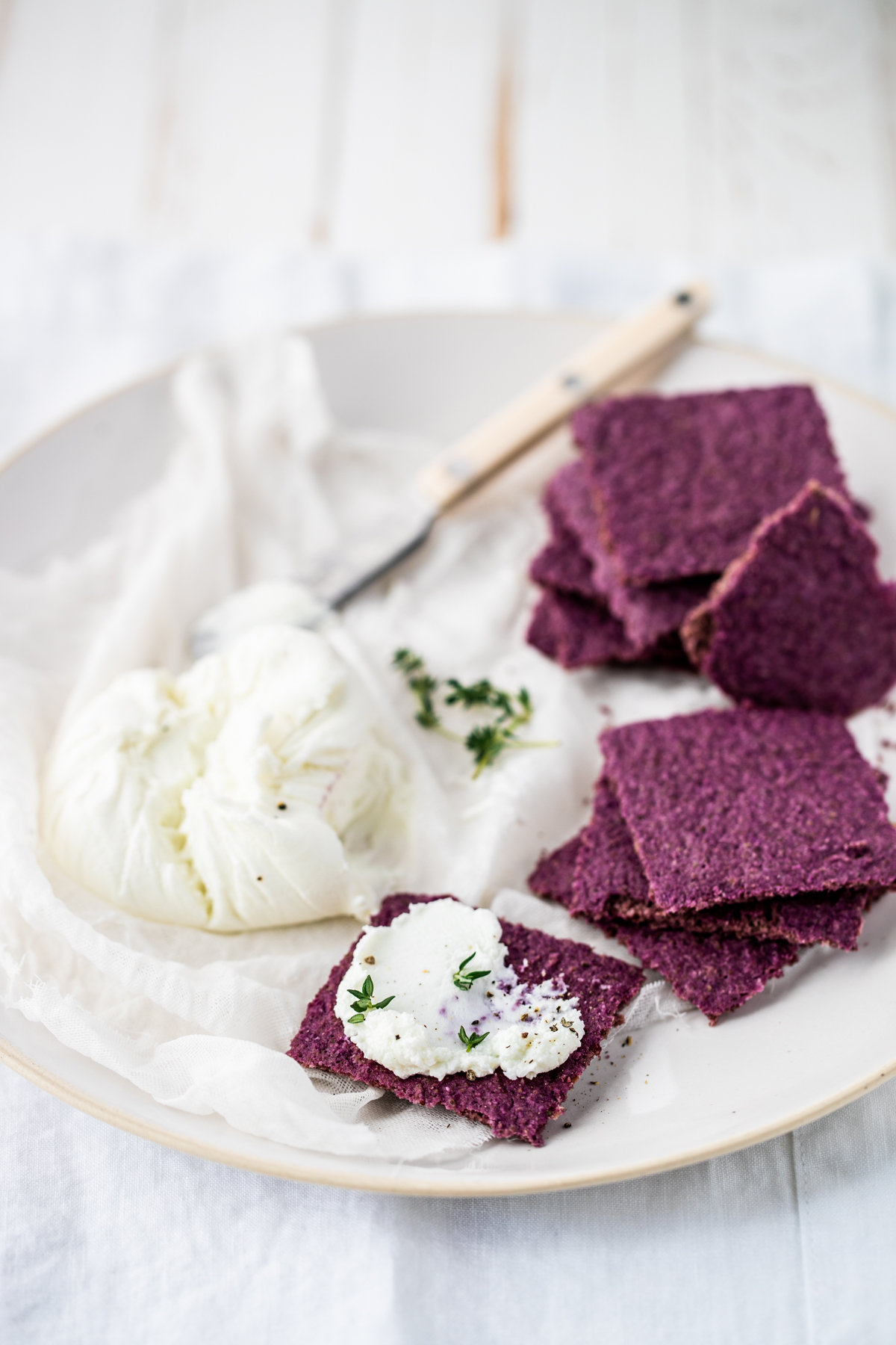 Sauerkraut crackers on a white plate and background, with a butter knife and tree nut cheese.