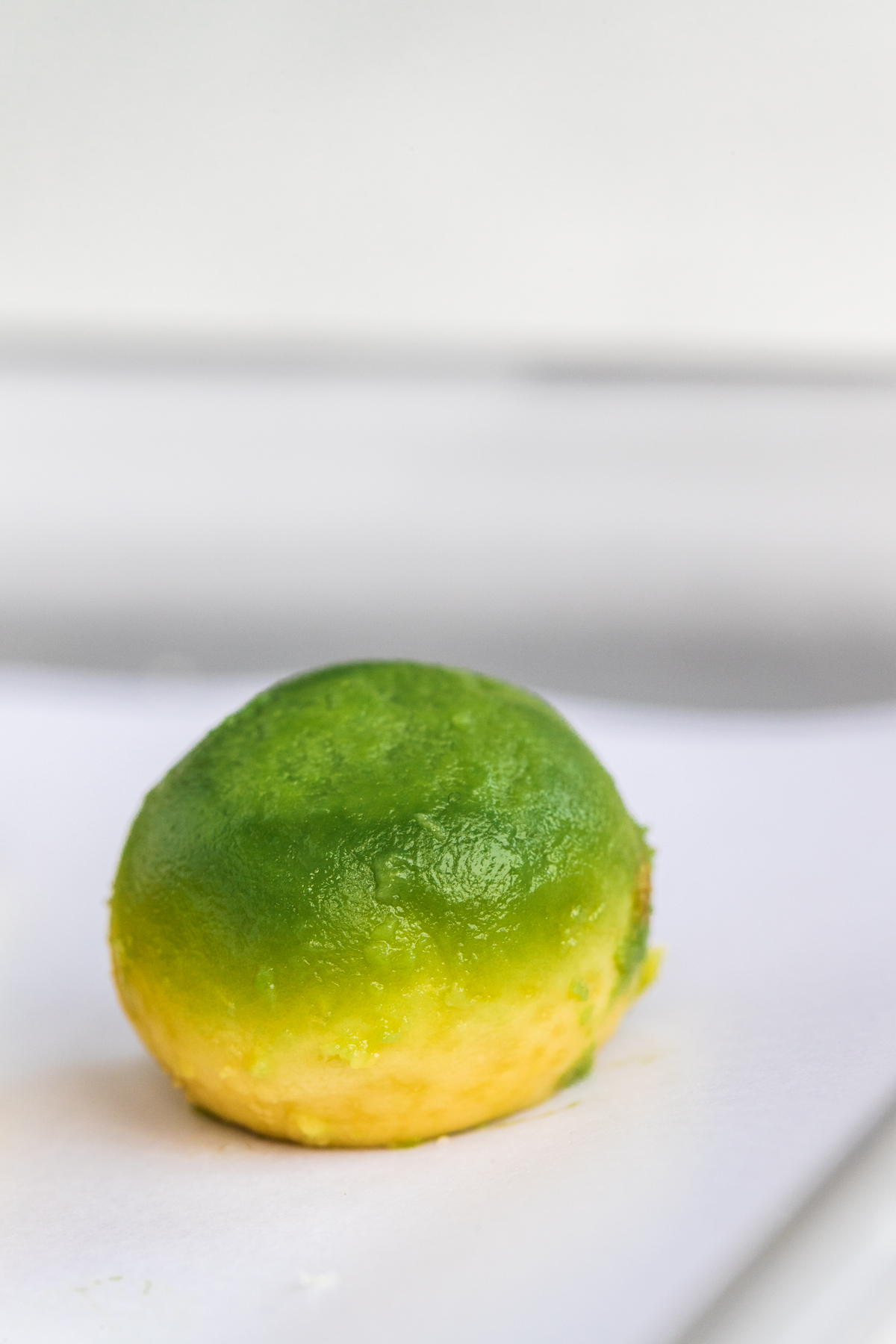 Perfect avocado ball made with a melon baller, on a white background