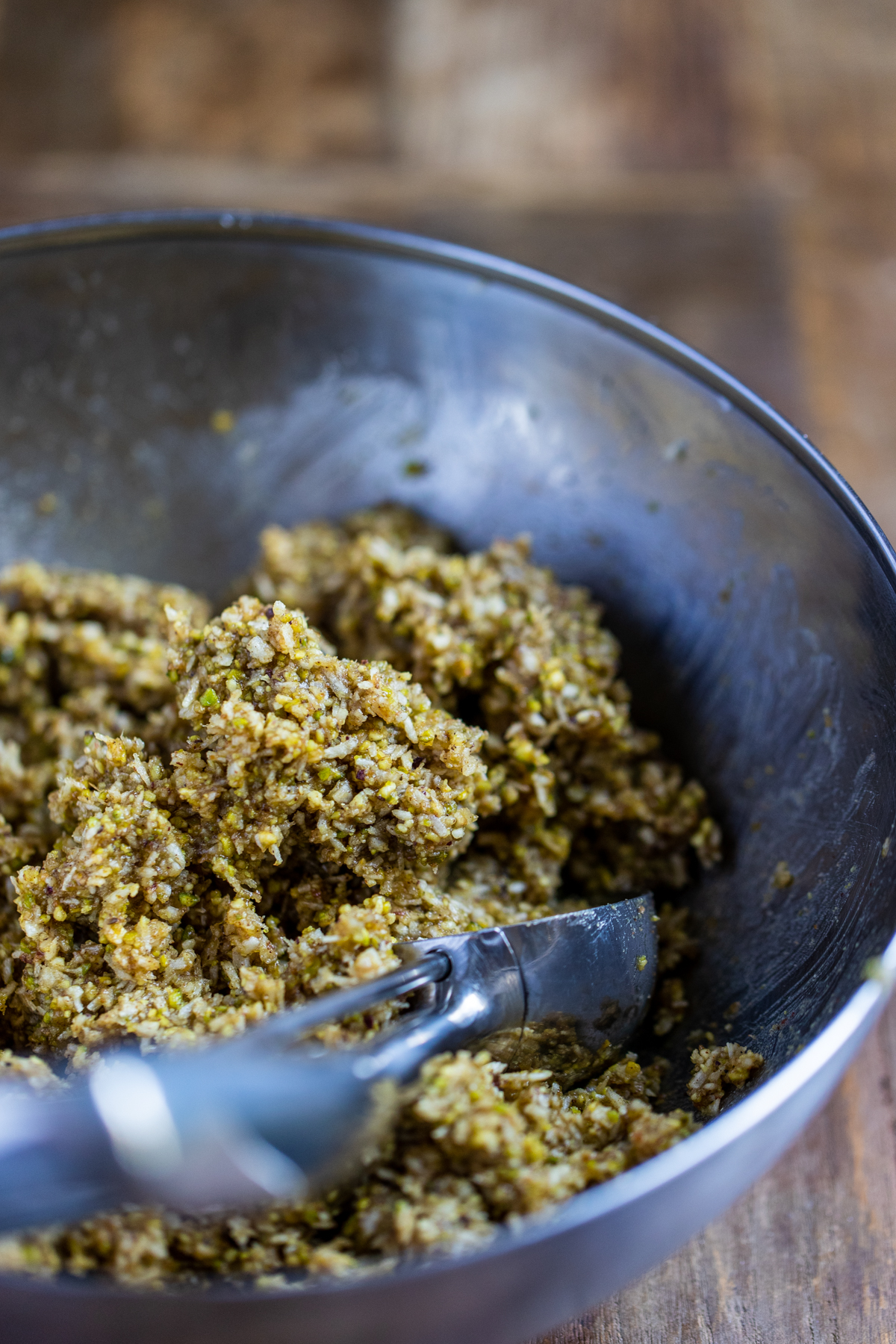 Pistachio Five Spice Macaroon mixture in a silver bowl with an ice-cream scoop