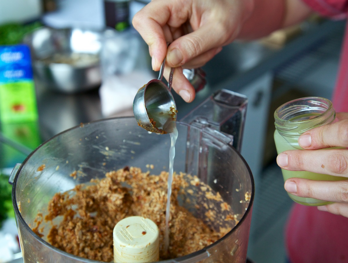 Adding lime juice to smoky maple sunflower seed mixture in a food processor 