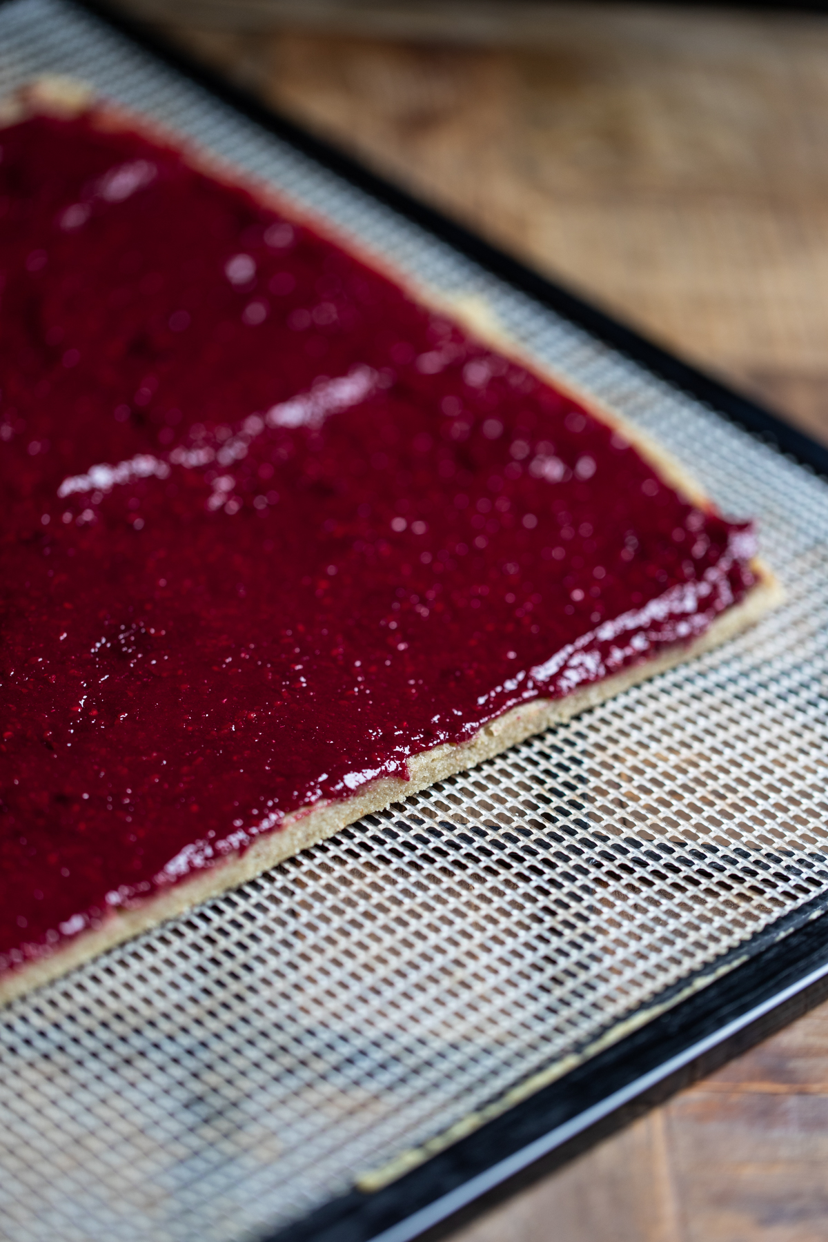 Raspberry jam spread evenly on swiss roll pastry